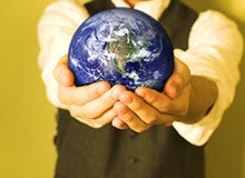 A person in formal attire holding a small globe, symbolizing global responsibility or unity.