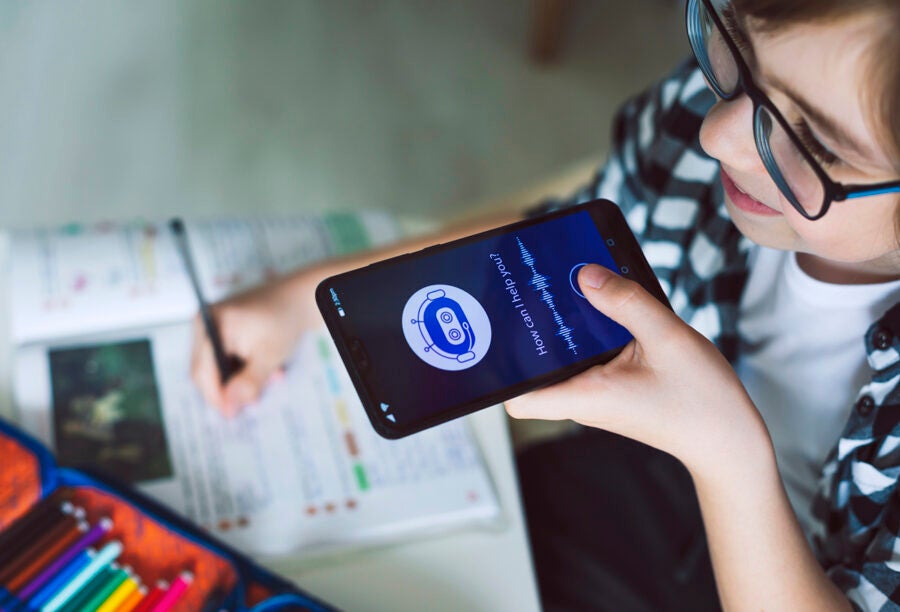 Young kid talking to a phone chatbot while doing schoolwork to show how generative AI harms education without guardrails