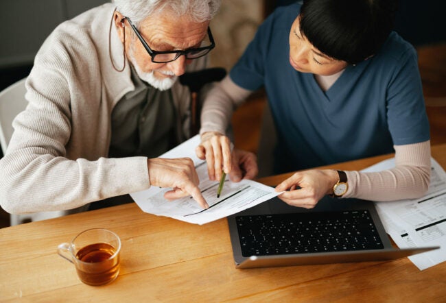 A caregiver reviewing health and financial documents with an elderly man